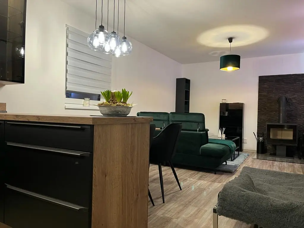 Obývací pokoj s krbovými kamny a designovým závěsným osvětlením v modulovém domě Rokytnice
