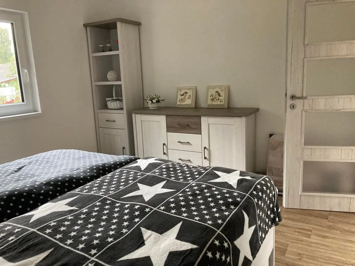 Ložnice s francouzskou postelí, světlou komodou a regálem v modulovém domě Solnice